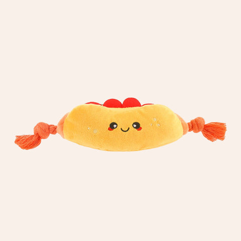 Plush toy resembling a hot dog with a smiling face on a white background