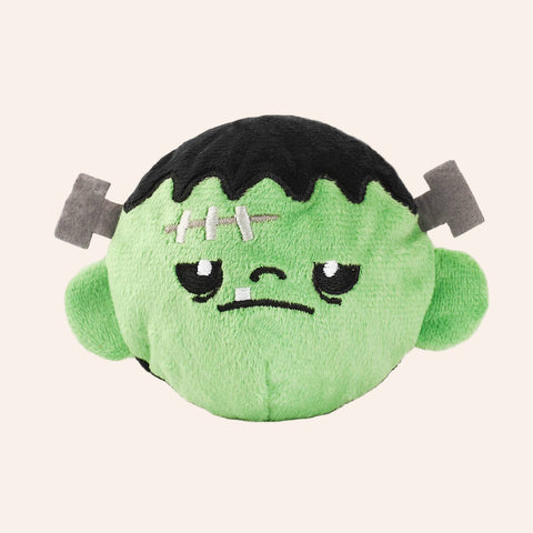 Plush toy resembling a green character with black hair on a white background
