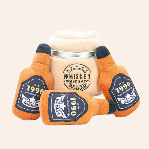 Plush toy shaped like a whiskey bottle with a glass in the center on a white background
