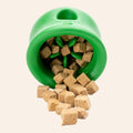 Green pet toy with treats spilling out on a white background