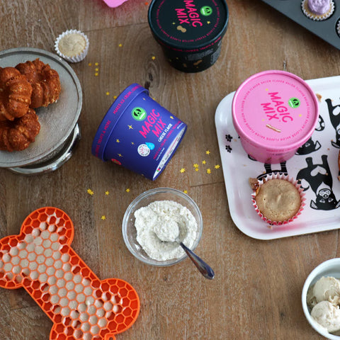 Magic Mix baking mix containers on a wooden surface with baked goods and ingredients.